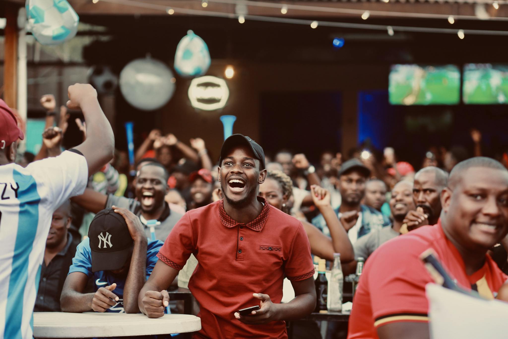 A lively group of fans enthusiastically cheering at a sports bar during a live match.